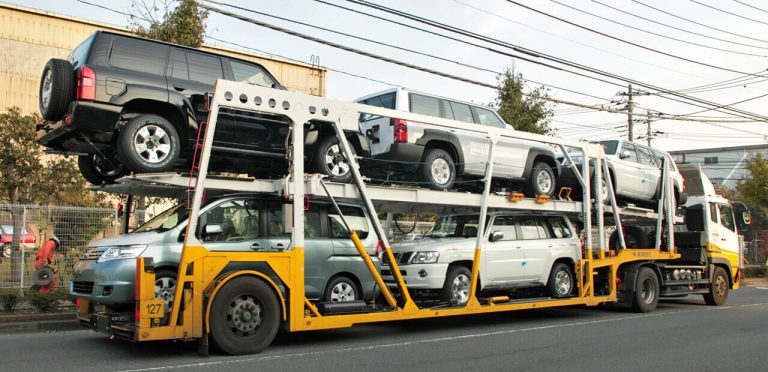 Car transport truck carrying multiple SUVs, securely loaded for delivery