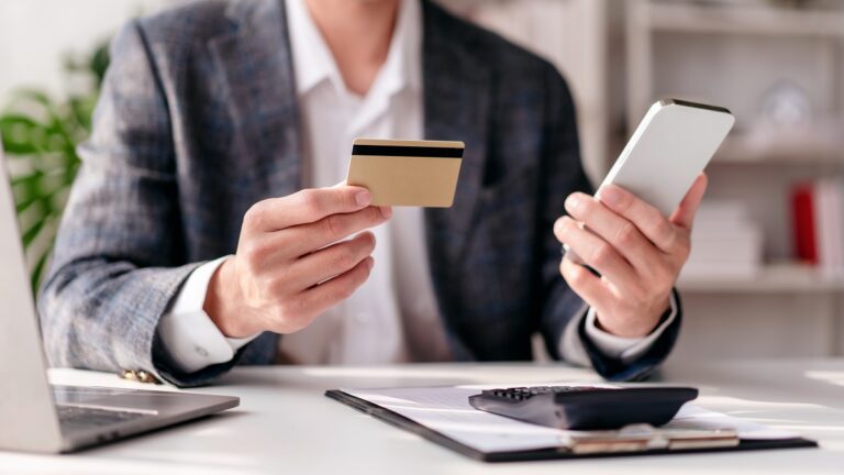 A person holding a credit card and smartphone