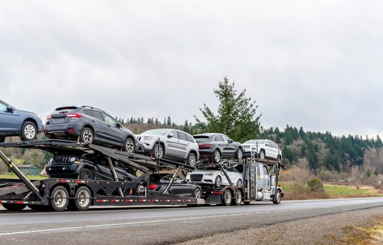 Car hauler semi-truck transporting vehicles on a winding autumn road