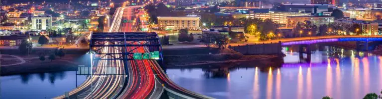 Scenic view of Charleston, West Virginia, with vibrant city lights and a bridge over the river at sunset