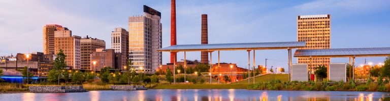 Alabama cityscape with buildings and a park near a waterway