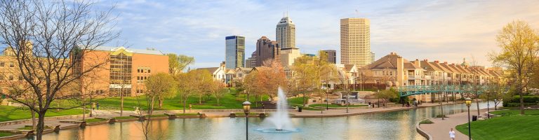 Indiana cityscape with a fountain, park, and modern buildings in the background