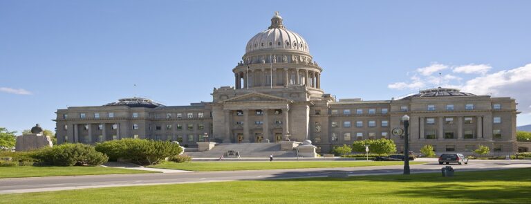 Idaho State Capitol building in Boise featuring classic architecture surrounded by green lawns under a clear blue sky