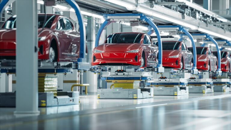 Automated assembly line in a factory producing red electric cars, showcasing modern manufacturing technology