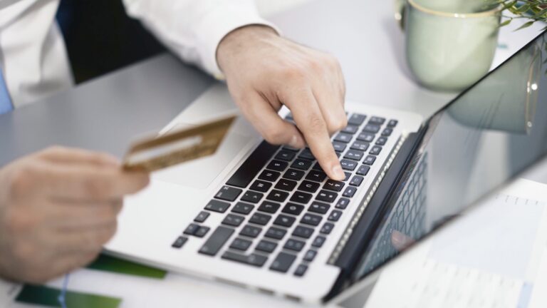 Person using a laptop and credit card for online car shopping with AutoTempest.